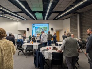 a large conference room with people standing and also seated at tables