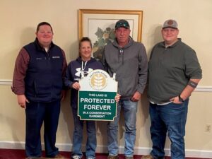 four people posing with a sign that says "protected forever"