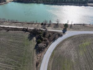 aerial view of a road and a driveway meeting near a small body of water