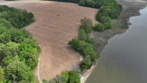 aerial view of an agricultural field and shoreline of a river with a few trees