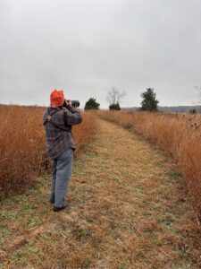 a person stands in a grassy field with a scope
